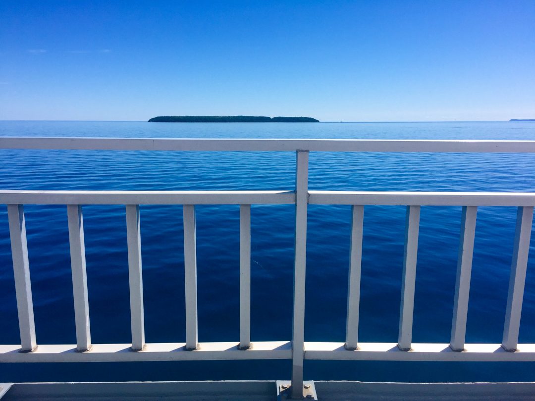 Looking over a white fence on a ferry to Manitoulin Island