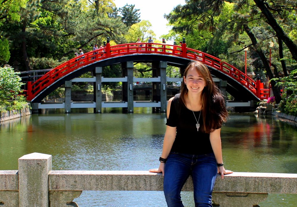 Kiyoko in front of a beautiful red bridge while studying abroad in Japan