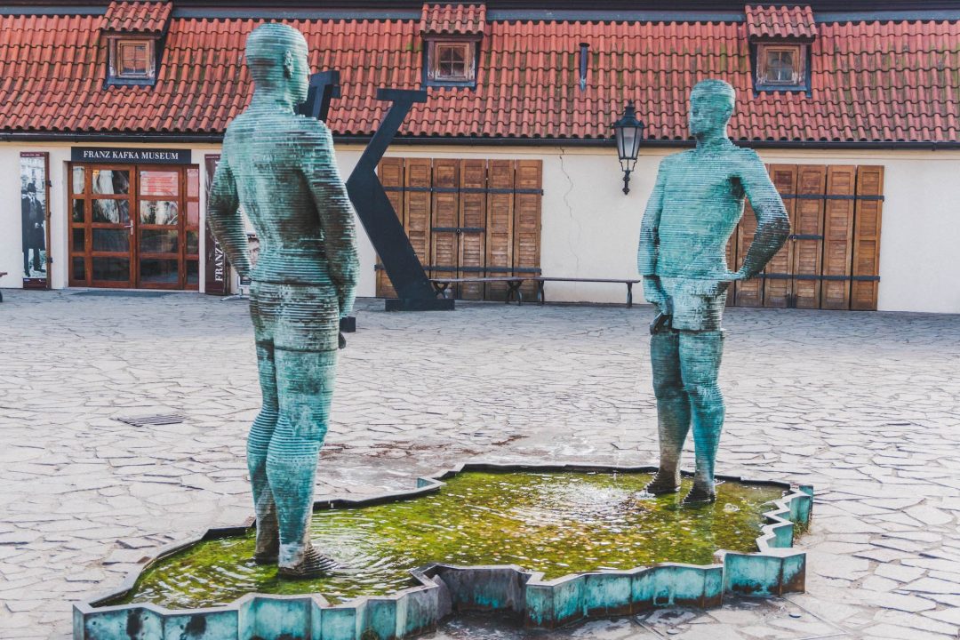 Two men peeing into a fountain shaped like the Czech Republic in front of the Kafka Museum in Prague