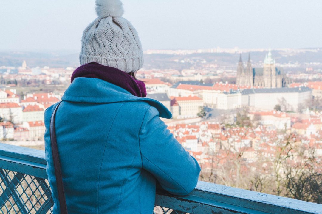 Girl in winter wear looking out at Prague Castle from Petrin Tower