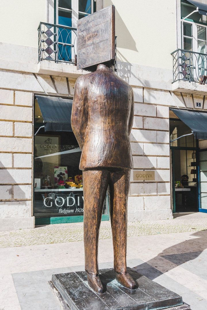 A statue of a man with his head in a book in Lisbon, Portugal
