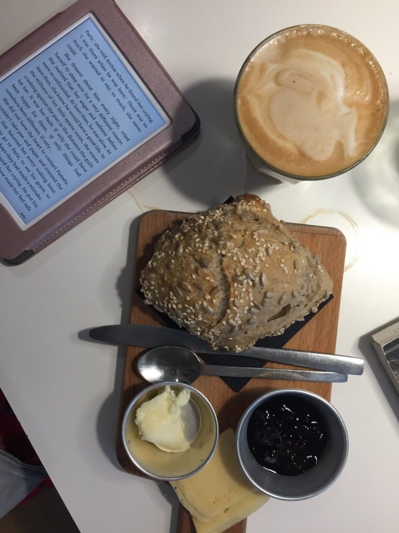 A Latte, Bread and jam, and a kindle at Copenhagen Coffee Lab in Lisbon, Portugal