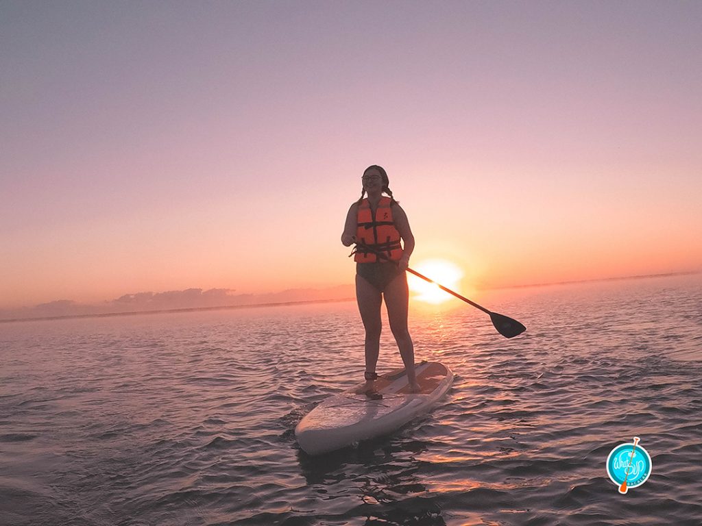 addie on a stand up paddleboard at sunrise in bacalar mexico