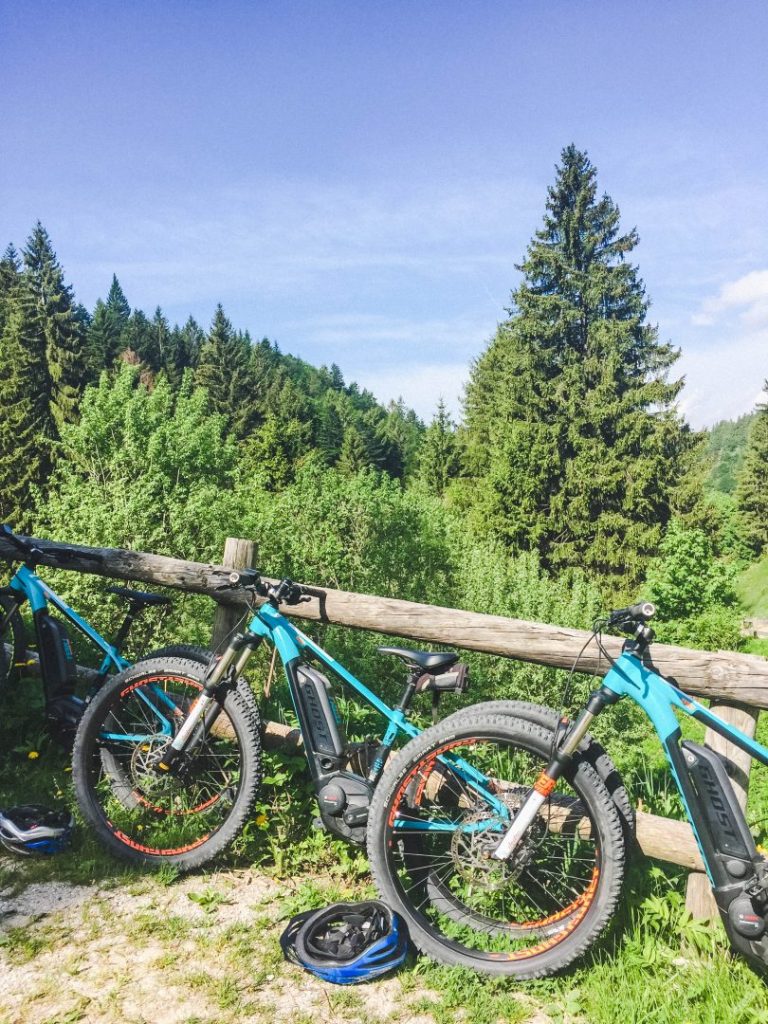 Blue mountain bikes lined up along a wooden fence in the mountain