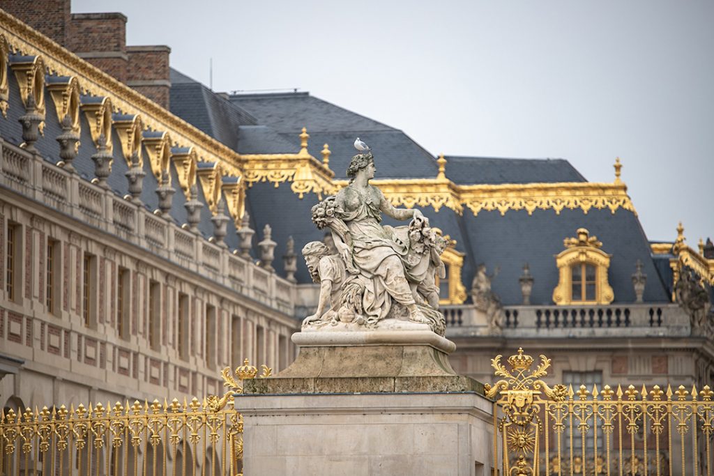 a statue and golden gates of versailles, france