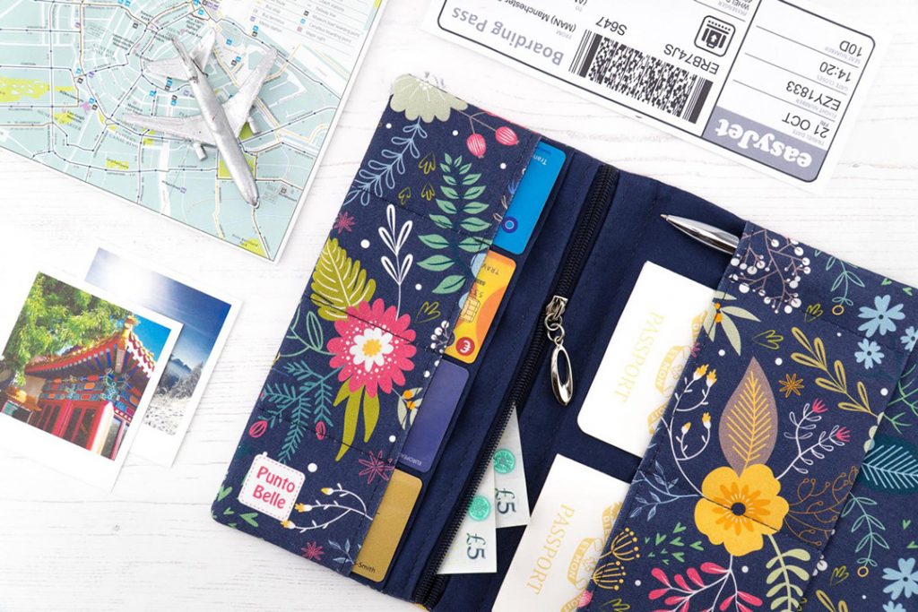 a flowery travel wallet among travel pictures, map, and plane ticket