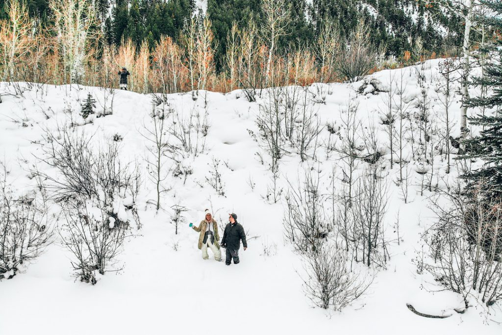 a man and woman knee-deep in snow in a forest in Aspen, Colorado, one of the most beautiful places to visit in winter in usa