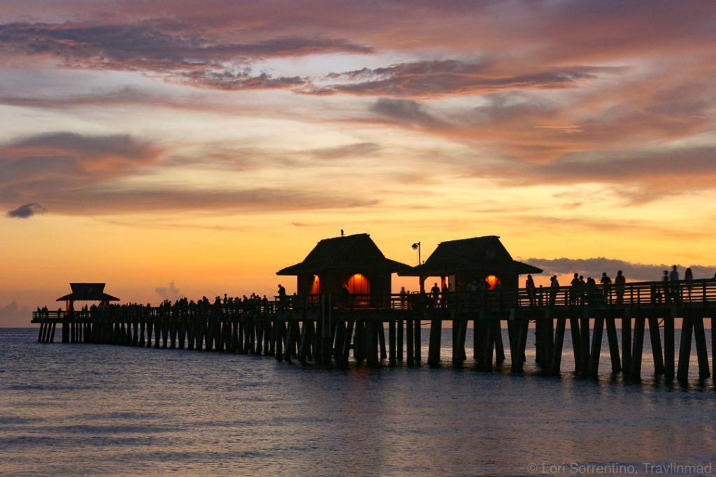 a colorful winter sunset behind a silhouetted pier in Naples, Florida