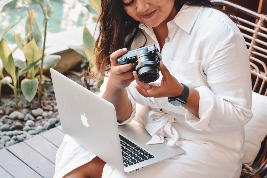 a woman in a white dress with a laptop and camera