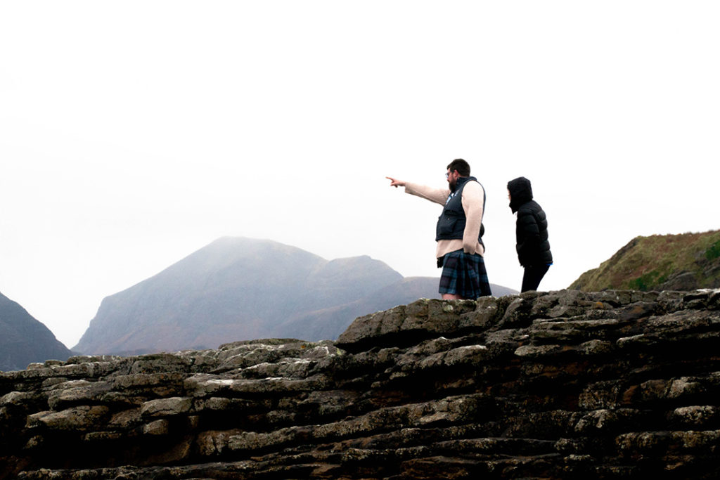 two men - one in a kilt - standing on a cliff and pointing. the best guides on this isle of skye tour from edinburgh.