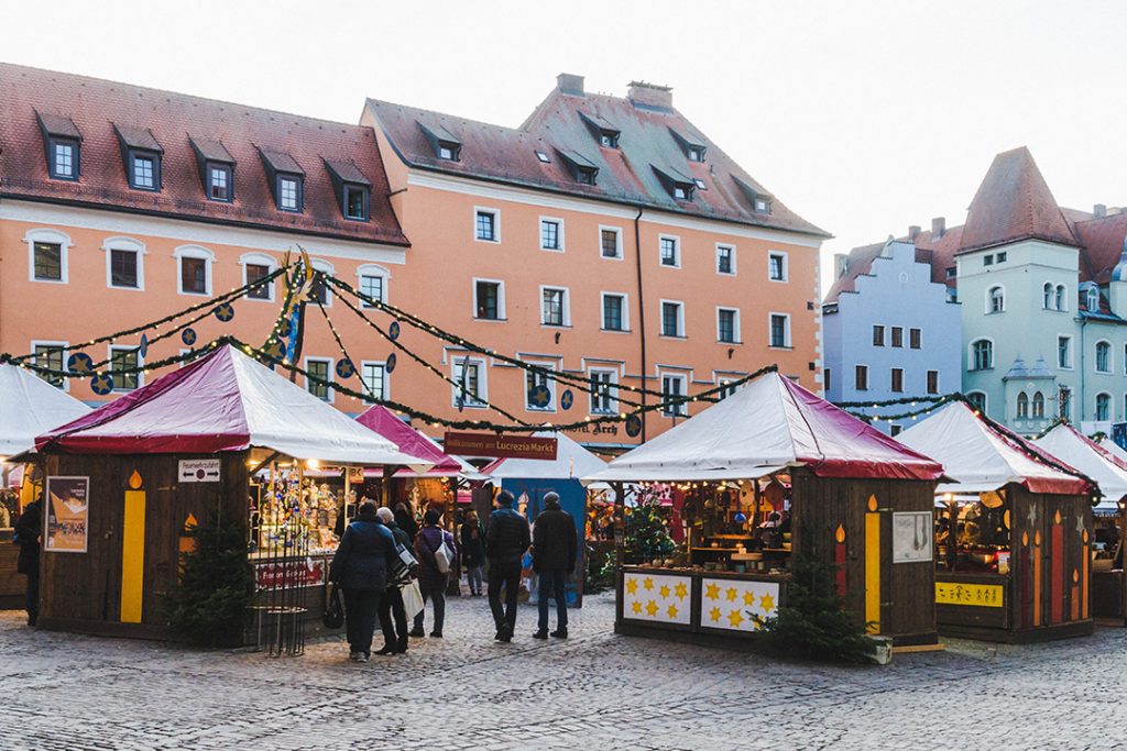 wooden booths with red roofs in a small square in Regensburg at the Lucrezia Market, one of the Regensburg Christmas Markets