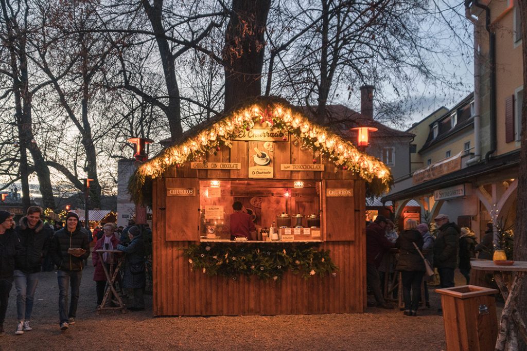 a small wooden booth with fairie lights trimming the roof at one of the regensburg christmas markets