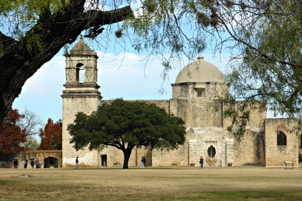 The San Antonio Mission, a light brown brick building with a tower and dome