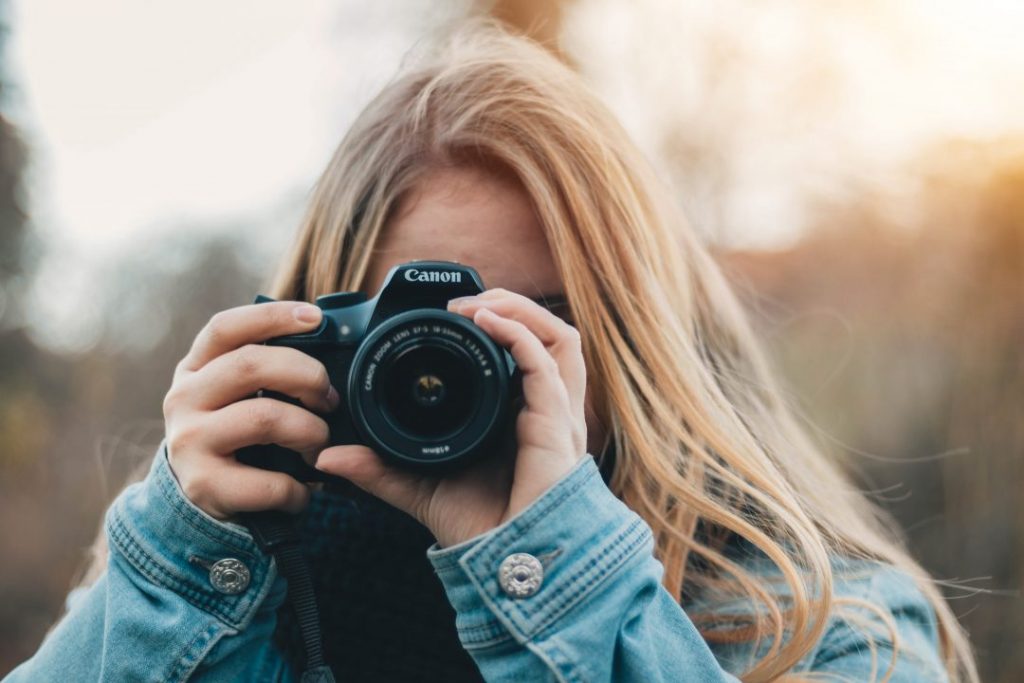 A girl holding a camera - how to choose the best camera for travel photography