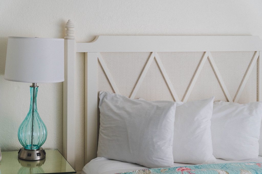 white pillows against a white headboard with a blue lamp on a side table