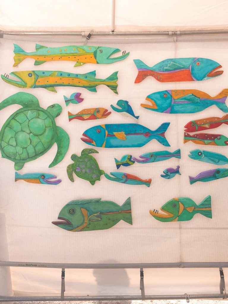 a wall full of paintede wooden sea animals