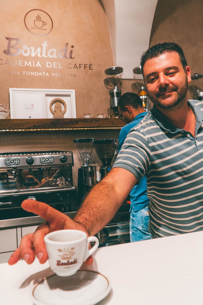 a man handing over an espresso across a bar