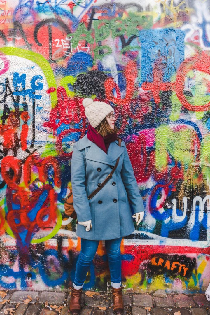 Girl in front of the graffitied Lennon Wall in Prague