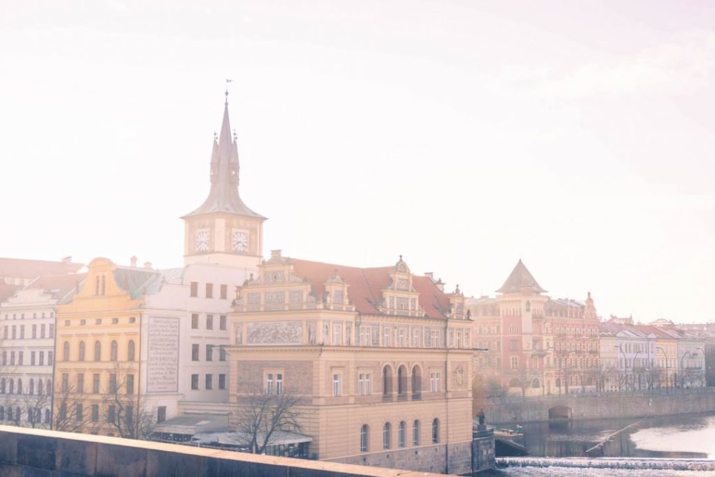 Sun shining through the clouds on the Prague riverfront from the Charles Bridge