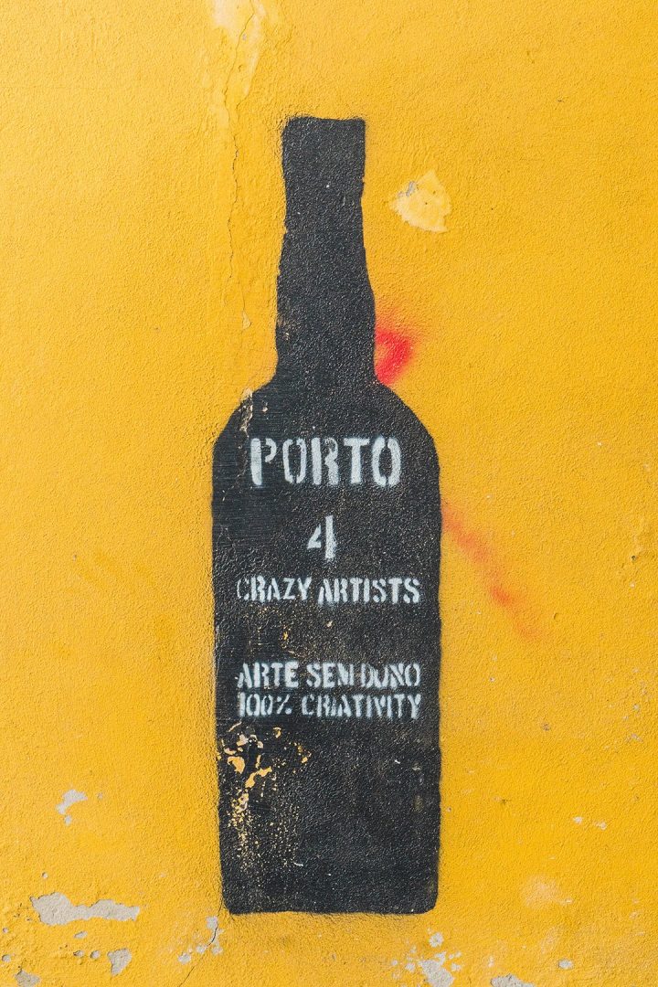 A painting of a wine bottle on a yellow wall in Porto, Portugal