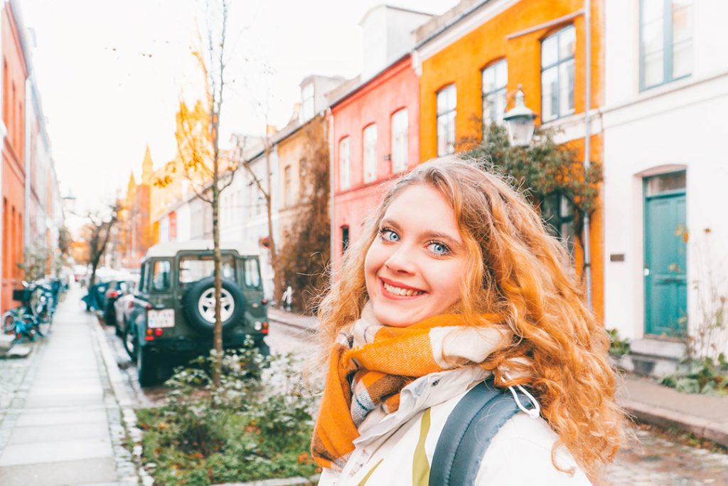 Megan smiling in front of colorful houses in Nyboder Copenhagen