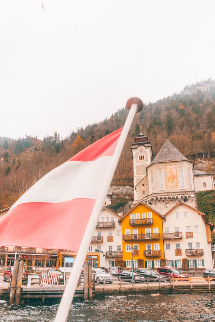 The Austria flag flying from the back of the ferry as it approaches Hallstatt