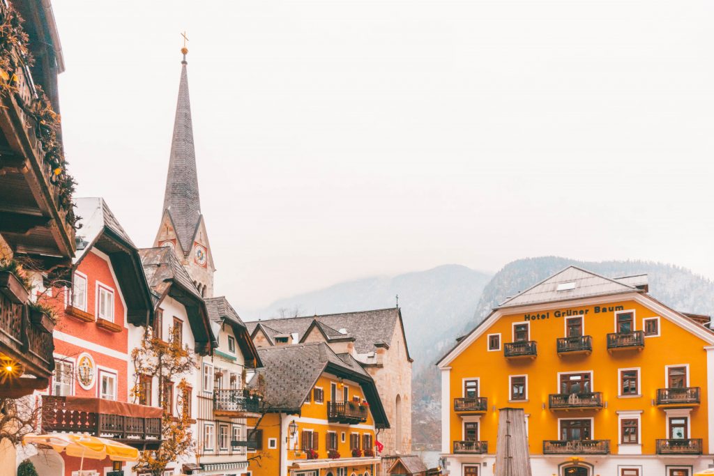 Hallstatt's main square with several colorful houses and a church spiring peeking out from behind them