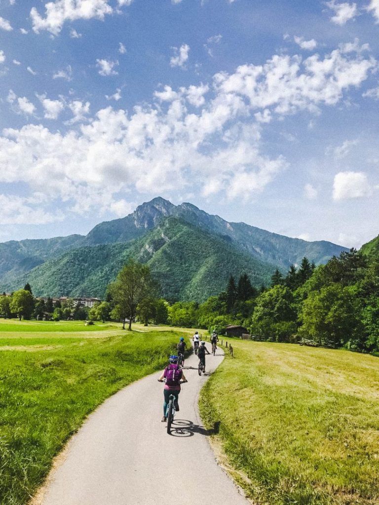 A group of mountain bikers riding along a smooth trail towards a mountain
