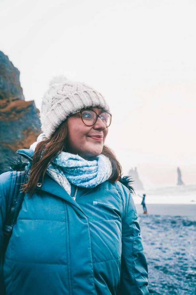 A close up of Addie standing on a black sand beach in Iceland