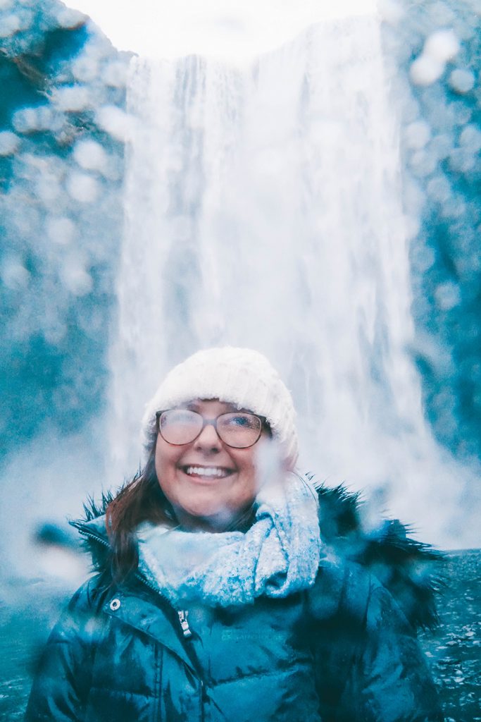 addie smiling in front of skogafoss waterfall