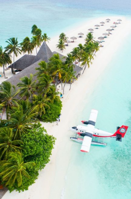 a small sea plane in very blue ocean on a beach with palm trees