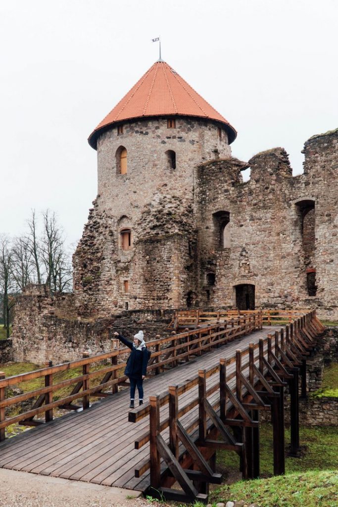 addie standing on a bridge in front of cesis castle