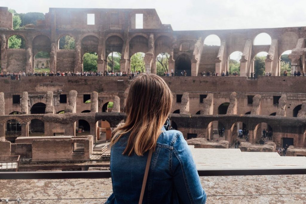 addie in a jean jacket looking out at the colosseum - don't make any of these rome travel mistakes and book your tickets in advance