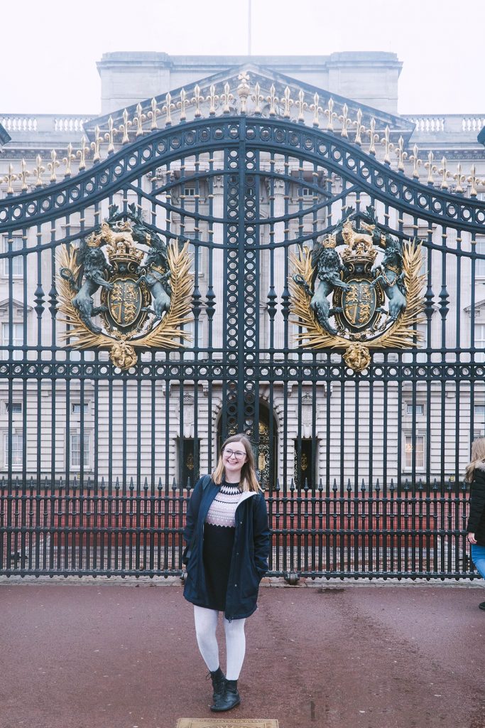 addie standing in front of the gates of buckingham palace