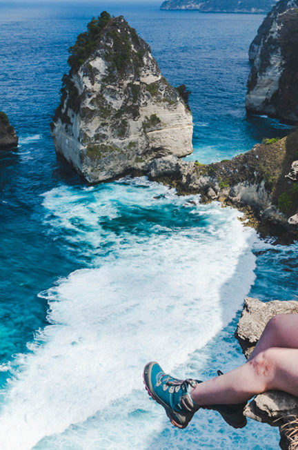 addie sitting on a cliff looking out at diamond beach on nusa penida